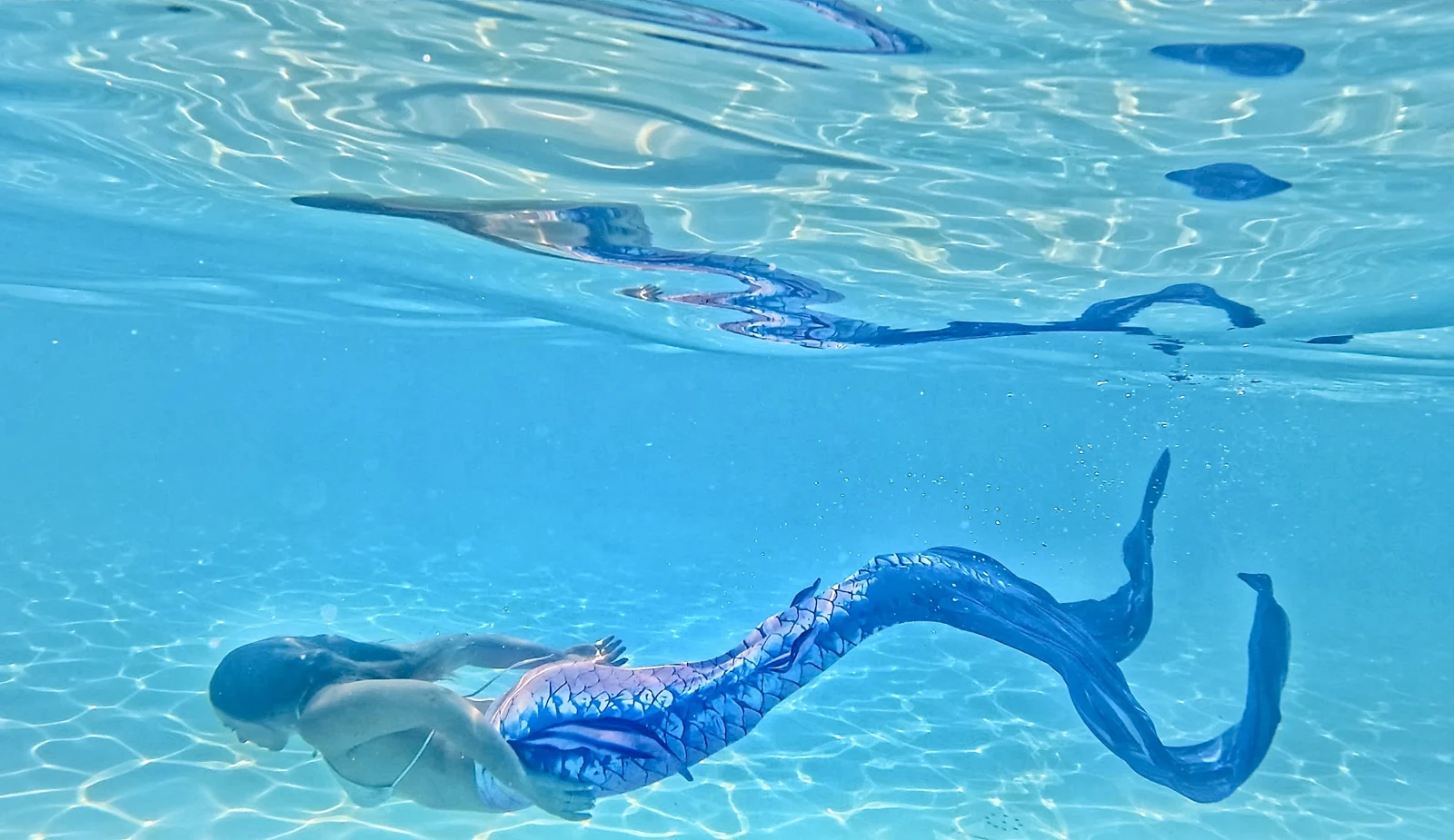 Two mermaids moving together beneath the surface