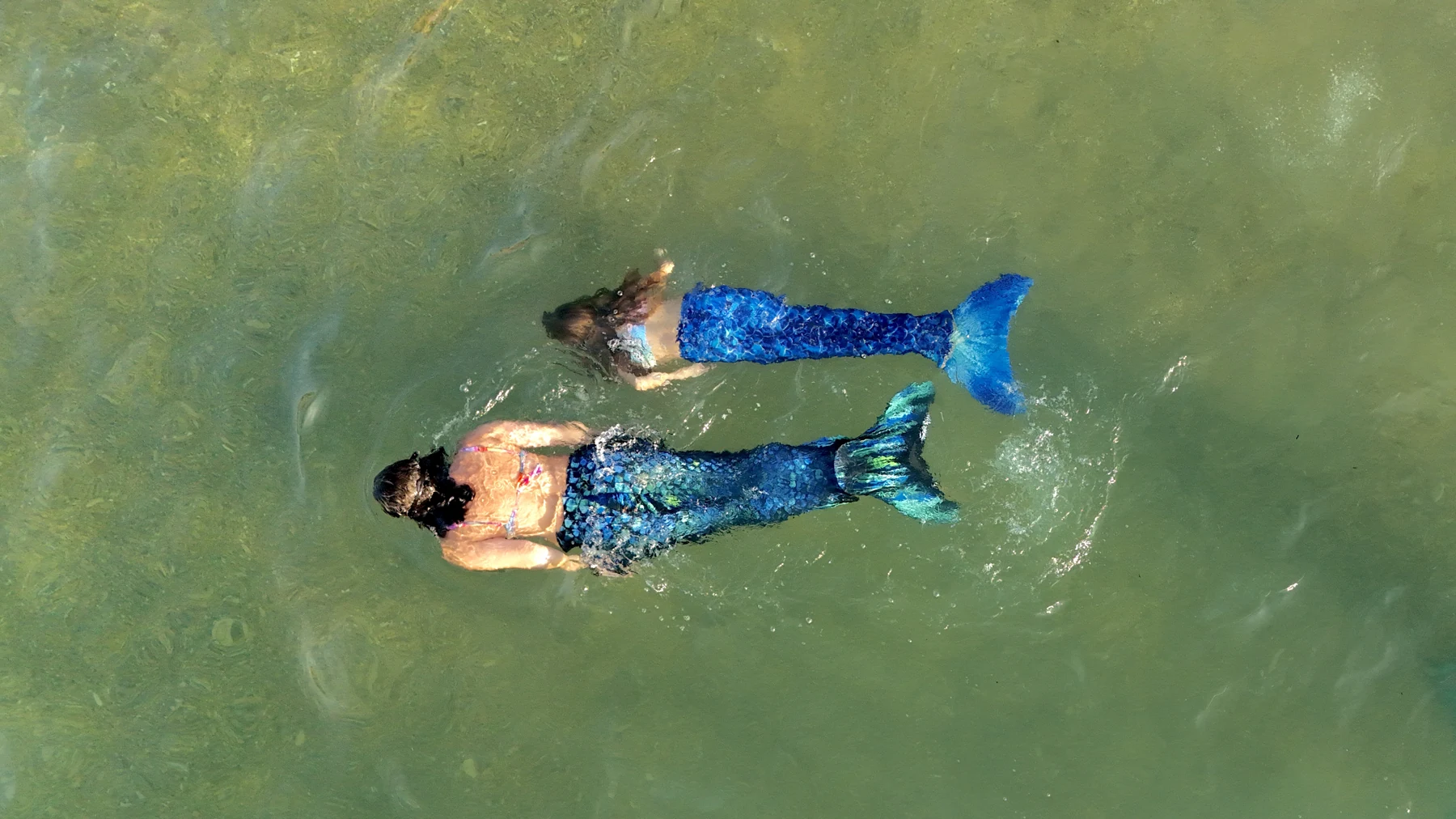 A mother and daughter swim side by side in the sea